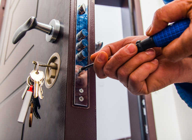 Der Schlüsselservice-Schlosser installiert einen neuen Sicherheits-Schließzylinder an einer Tür